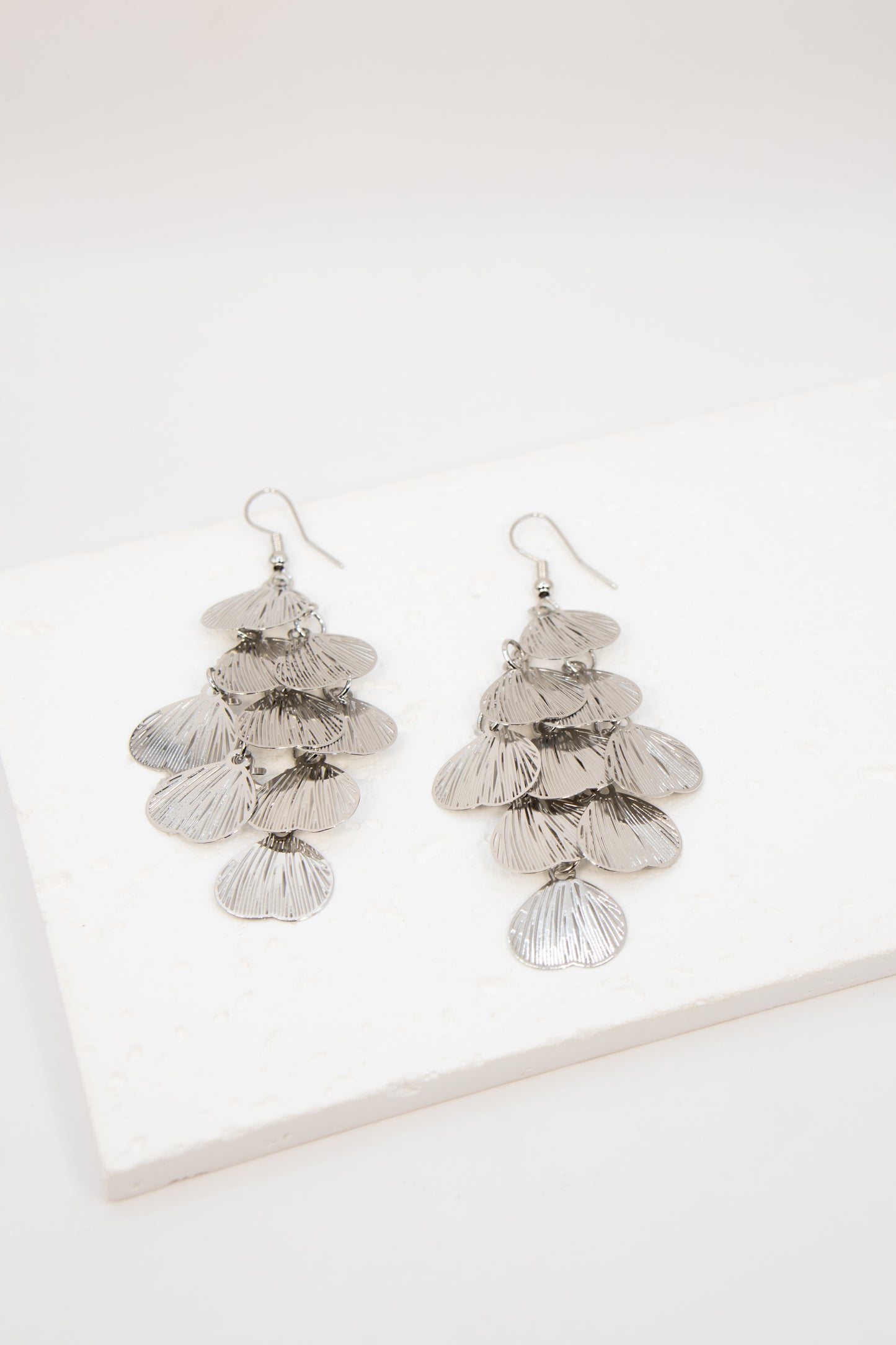 Pair of silver leaf-shaped earrings on a white background
