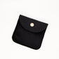 Black fabric pouch with a gold button on a white background