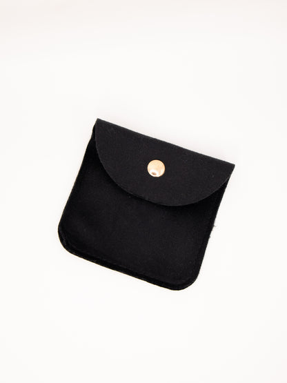 Black fabric pouch with a gold button on a white background