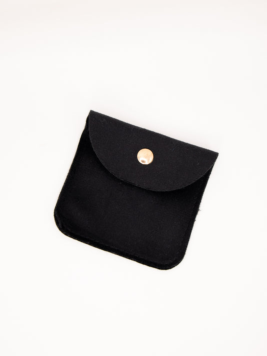Black fabric pouch with a gold button on a white background