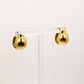 Gold teardrop earrings on a clear stand against a white background