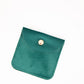Green velvet pouch with a gold button on a white background