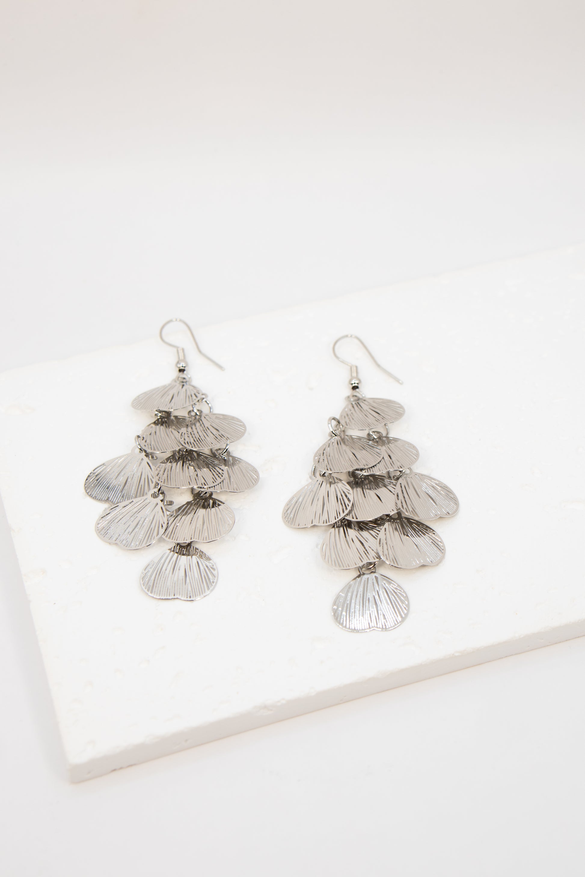 Pair of silver leaf-shaped earrings on a white background