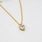 Gold necklace with a heart-shaped diamond pendant on a white background