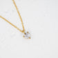 Gold necklace with a heart-shaped diamond pendant on a white background