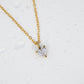 Gold necklace with a diamond pendant on a light gray background