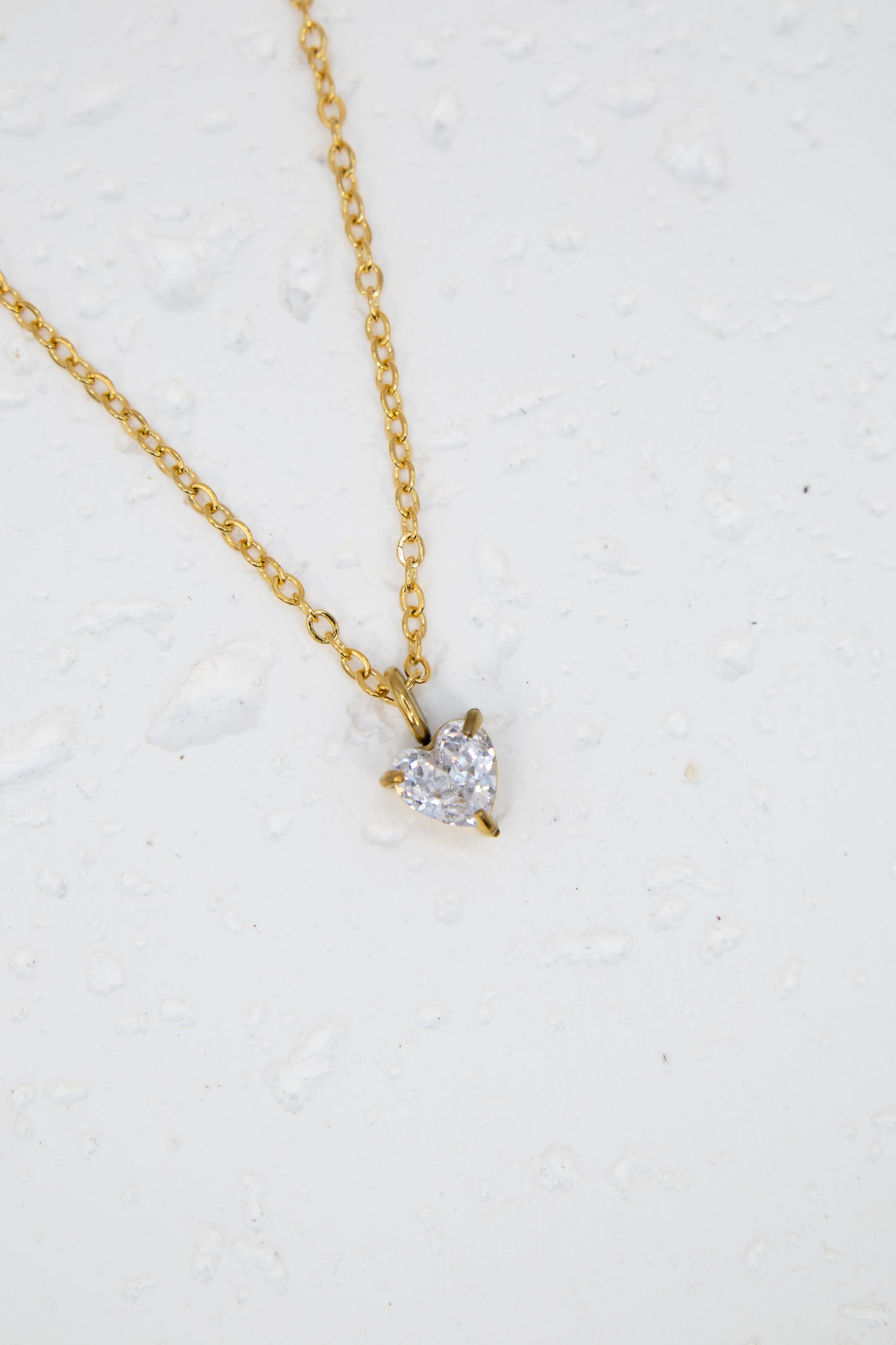 Gold necklace with a diamond pendant on a light gray background