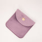 Purple fabric pouch with a gold button on a light pink background