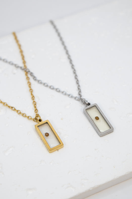 Two necklaces with rectangular pendants on a white surface