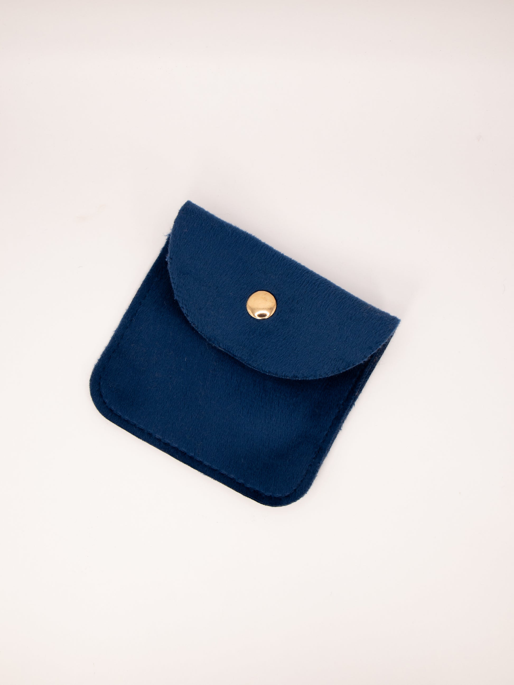 Navy blue pouch with a gold button on a light beige background
