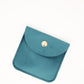 Teal pouch with a gold button on a white background