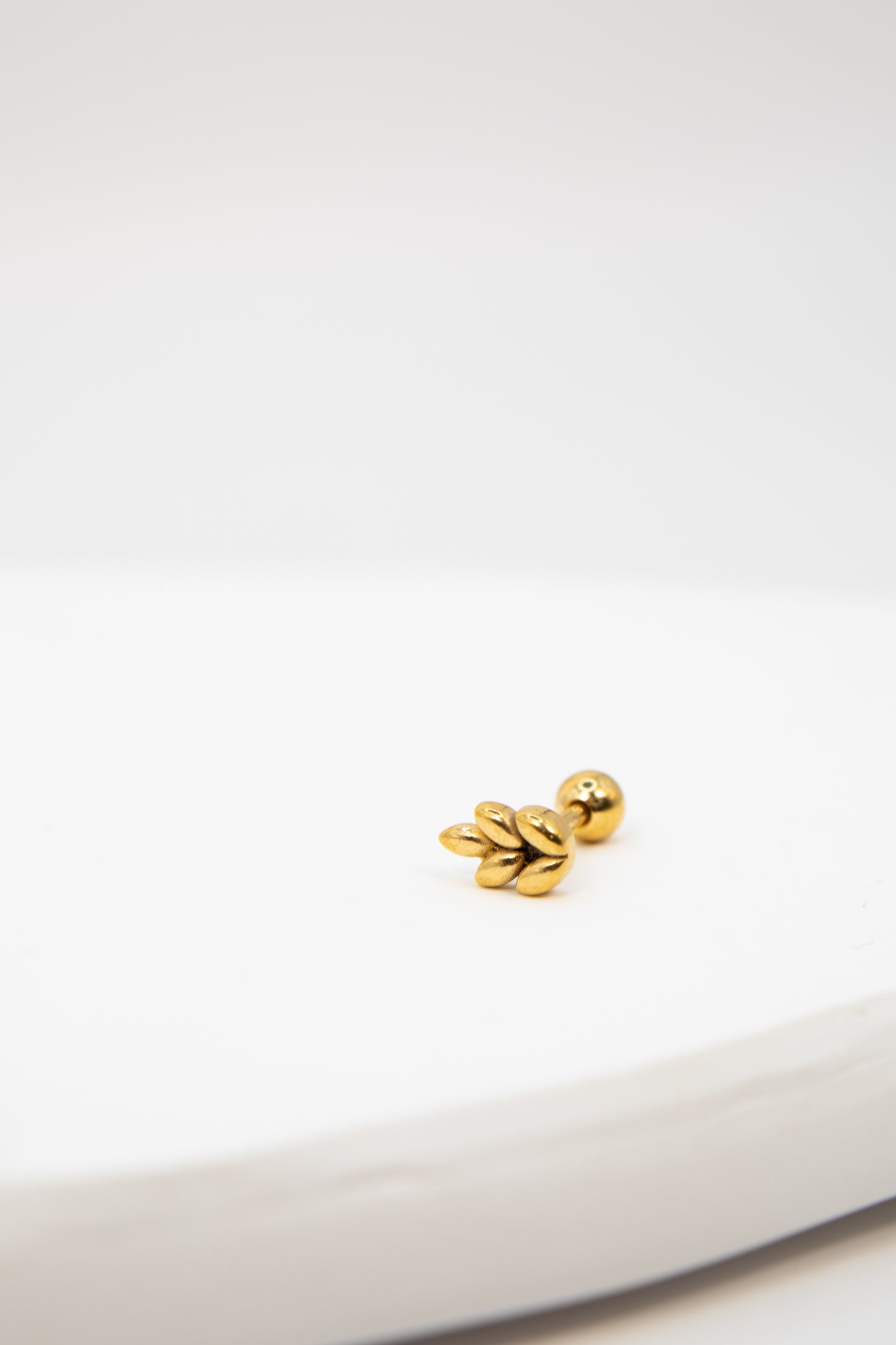 Gold earring with leaf design on a white background